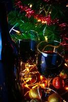 vinho tinto em vidro transparente, árvore de natal e enfeite na mesa de madeira pronta para comemorar. foto