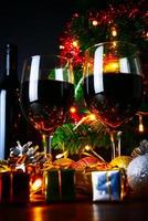 vinho tinto em vidro transparente, árvore de natal e enfeite na mesa de madeira pronta para comemorar.