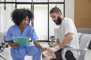 enfermeira africana está examinando tendinite em lesão no joelho por acidente esportivo em paciente do Oriente Médio para tratamento e processo de reabilitação foto