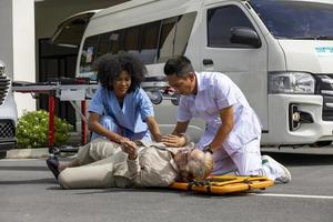 equipe de paramédicos está ajudando o paciente sênior de acidente de carro usando prancha espinhal para transferir para a ambulância para primeiros socorros e conceito de acidente de rua foto