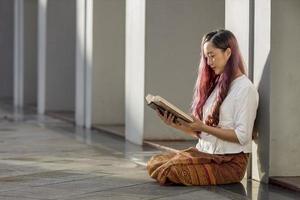 mulher budista asiática está lendo o antigo livro tripitaka em sânscrito do senhor buda dhamma ensinando enquanto está sentado no templo para cantar e adorar no mosteiro foto