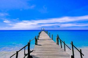 um píer de madeira que se estende até o mar, vista para a paisagem marinha com céu nublado e azul para viajar no feriado relaxar no verão foto