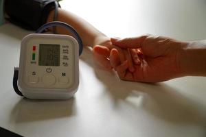 monitoramento da pressão arterial de pacientes usando monitor de pressão arterial de braço na sala de exame clínico. foto
