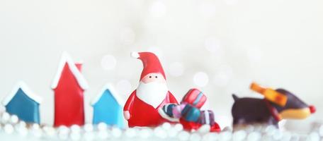 bonecas de papai noel e caixa de decorações de natal em fundo claro abstrato foto