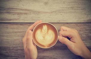 mãos de mulher segurando latte art, xícara de café com efeito de filtro retrô foto