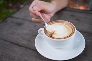 mãos de mulher com latte art, xícara de café foto