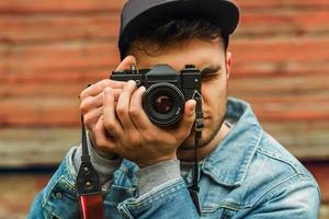fotógrafo elegante jovem hipster masculino tira uma foto com uma câmera vintage