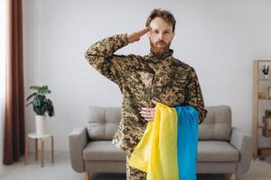 retrato de um soldado ucraniano em uniforme militar com uma bandeira amarela e azul em homenagem foto