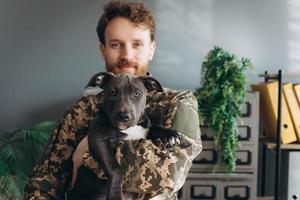 retrato de um soldado ucraniano e seu fiel amigo o cão amstaff no escritório foto