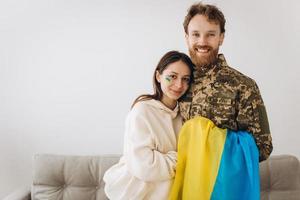 feliz casal ucraniano que se conheceu depois da guerra. um militar barbudo de uniforme abraça sua esposa feliz em casa. foto