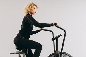 mulher de crossfit fazendo treinamento cardio intenso na bicicleta de exercício foto