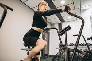 mulher de crossfit fazendo treinamento cardio intenso na bicicleta de exercício foto