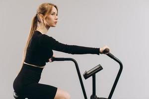 mulher de crossfit fazendo treinamento cardio intenso na bicicleta de exercício foto