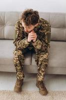 retrato de soldado patriota ucraniano barbudo jovem emocional em uniforme militar sentado no sofá do escritório foto