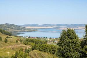 paisagem pitoresca do lago azul entre as montanhas no verão. casas de aldeia ao lado do lago. lago bolshoye, território de krasnoyarsk, sibéria, rússia. foto