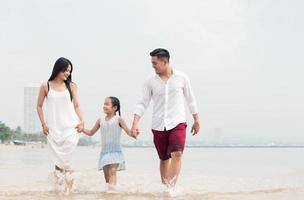 família feliz na praia correr e pular ao pôr do sol foto