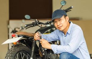 mecânico reparando moto na garagem da oficina, homem consertando moto na oficina, conceitos de reparação e manutenção foto