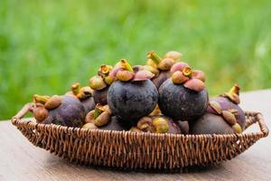 mangostão fresco em uma cesta de vime na parte de trás da cor verde natural. foto