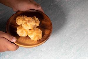 eclair em um prato de madeira com uma garrafa de vidro de água vermelha. foto