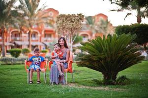 mãe com dois filhos no resort egípcio perto de palm sentado na cadeira. férias em família. foto