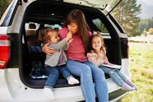 família no interior do veículo. mãe com suas filhas. crianças no porta-malas. viajando de carro nas montanhas, conceito de atmosfera. foto