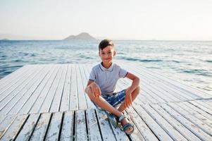 menino sente-se no resort de turquia no cais contra o mar mediterrâneo. foto