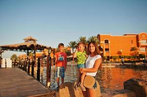 mãe com dois filhos na piscina do resort egípcio no pôr do sol. férias em família. foto