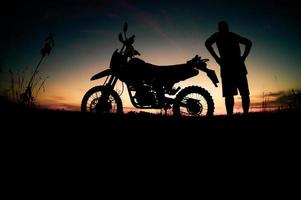 silhuetas masculinas e motos de motocross de turismo. parque para relaxar nas montanhas à noite. conceito de viagens e lazer de aventura foto