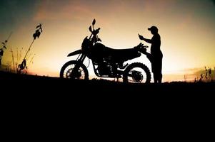 silhuetas masculinas e motos de motocross de turismo. parque para relaxar nas montanhas à noite. conceito de viagens e lazer de aventura foto