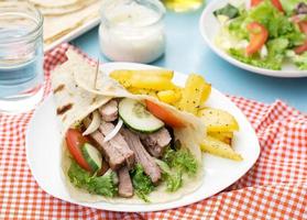giroscópios gregos com carne de porco, legumes e pão pita caseiro foto