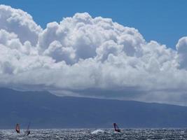 nuvens dramáticas três windsurfistas água azul foto