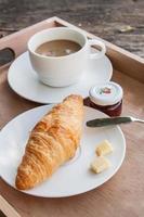 croissant e café em fundo madeira foto