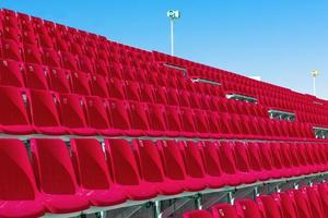 fileiras de assentos de estádio de plástico de cor vermelha vazios no terraço foto