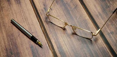 óculos de vista superior e caneta no fundo de madeira foto