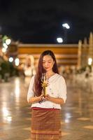 retrato jovem está sorrindo segurando vela e rezando em wat suthat thepwararam foto