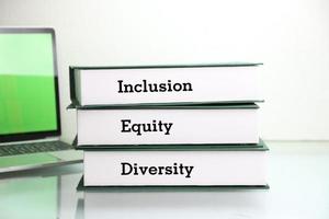livros com palavras dei, diversidade, equidade, inclusão na mesa com fundo branco. foto