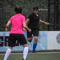 nova delhi, índia - 01 de julho de 2018 mulheres futebolistas do time de futebol local durante o jogo no campeonato regional derby em um campo de futebol ruim. momento quente da partida de futebol no estádio de grama verde foto