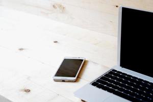 laptop e telefone inteligente em uma mesa de madeira. foto