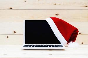 laptop com tela em branco e chapéu de papai noel foto