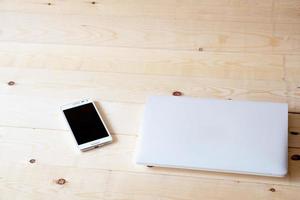 laptop e telefone inteligente em uma mesa de madeira. foto