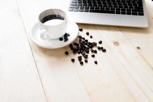laptop, xícara de café fresco e grãos de café foto