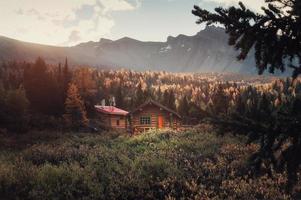 cabanas de madeira com montanhas rochosas e sol na floresta profunda de outono pela manhã no parque provincial de assiniboine foto