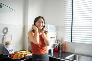 mulher ouvindo música através de fones de ouvido na cozinha em casa - conceitos de estilo de vida foto