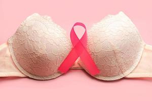 conceito de câncer de mama. vista superior do sutiã feminino e da fita rosa símbolo conscientização do câncer de mama foto