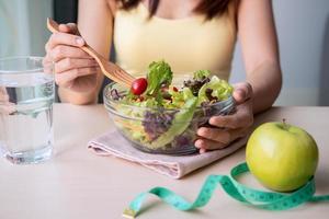 jovem mulher comendo salada saudável caseira em casa, estilo de vida saudável, conceito de dieta foto