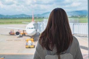 viajante jovem olhando para o avião no aeroporto, conceito de viagens foto