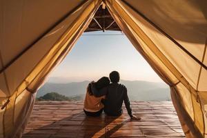 jovem casal viajante olhando bela paisagem ao pôr do sol e acampar na montanha, conceito de estilo de vida de viagens de aventura foto