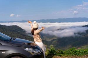 viajantes de jovem com carro assistindo um belo mar de neblina sobre a montanha enquanto viaja dirigindo viagem de férias foto