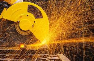 engenheiro técnico industrial em pano protetor azul usar máscara de segurança, homem trabalhando com ferramenta moedor elétrico na estrutura de aço com faíscas voando na fábrica, foco seletivo foto