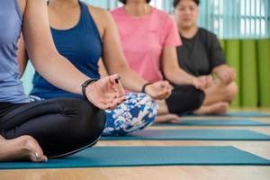 hora da ioga. mulher jovem e atraente se exercitando e sentado em pose de meia lótus de ioga com posição de gesto de mudra enquanto descansa em casa, bem-estar, conceito de bem-estar foto